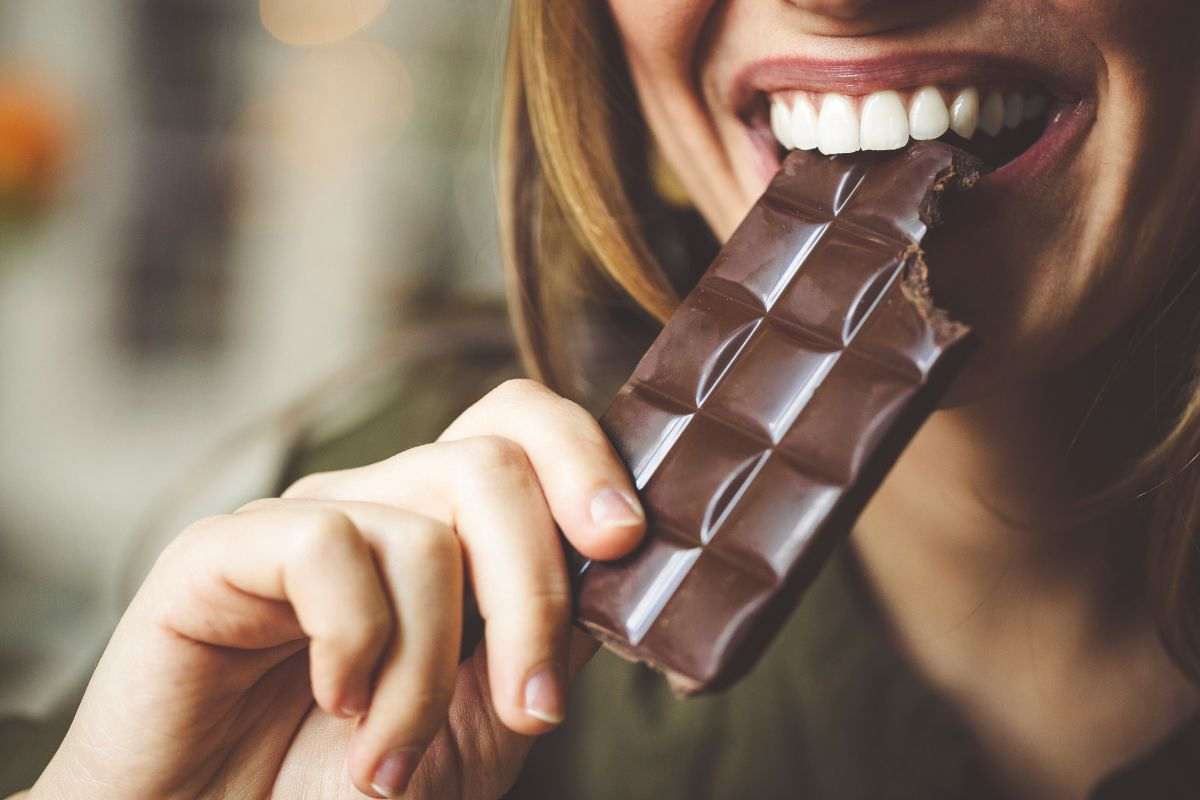 Ragazza addenta una tavoletta di cioccolato